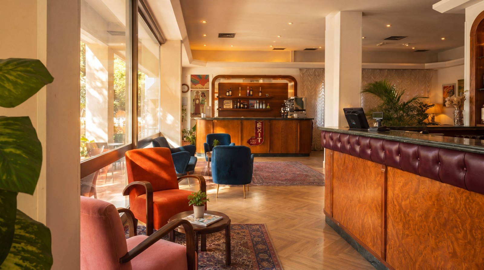 La lobby dell'Hotel Columbia — bar in legno, poltrone vintage e luce calda del pomeriggio